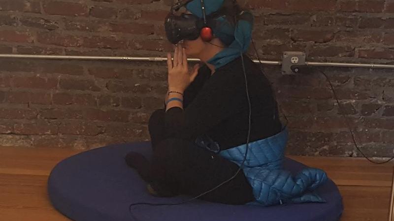 Person meditating in a VR headset on a cushion
